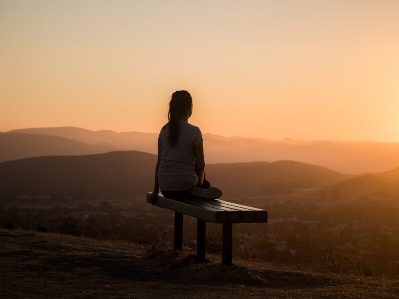 woman sitting on bench over viewing mountain
