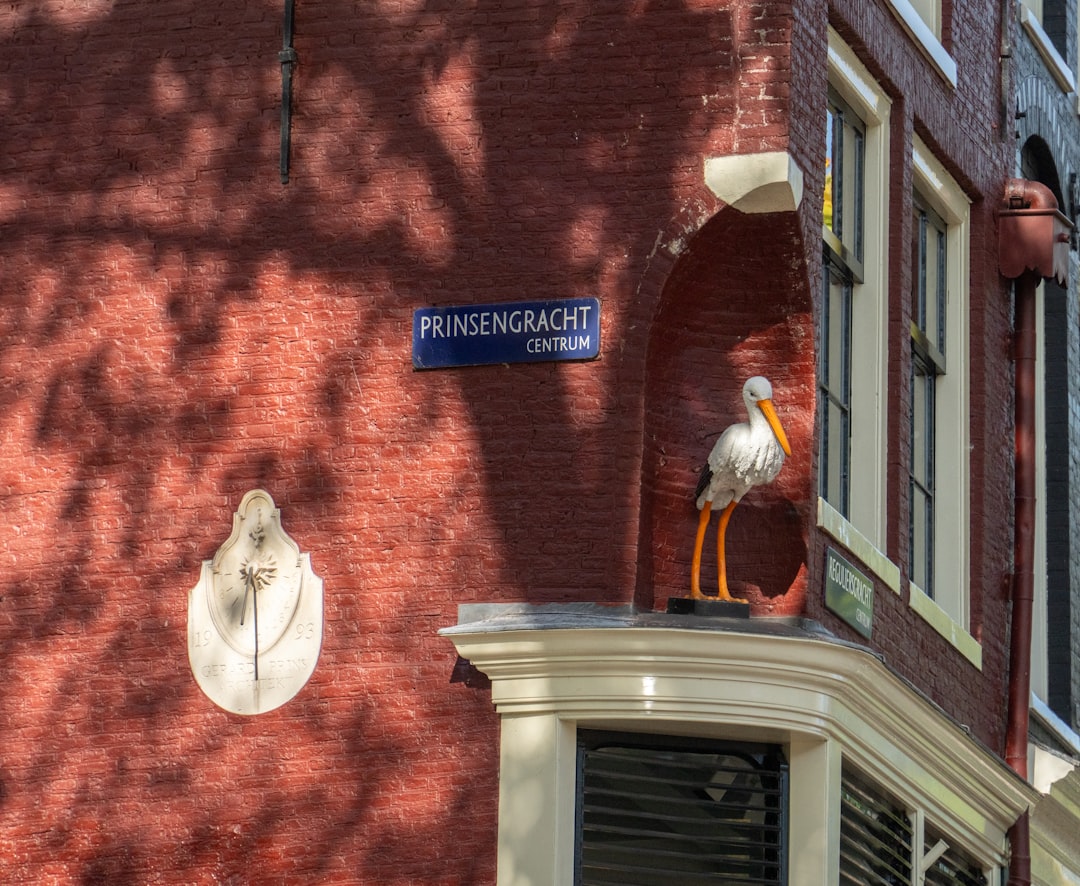 A white stork sculpture on a brick building corner.