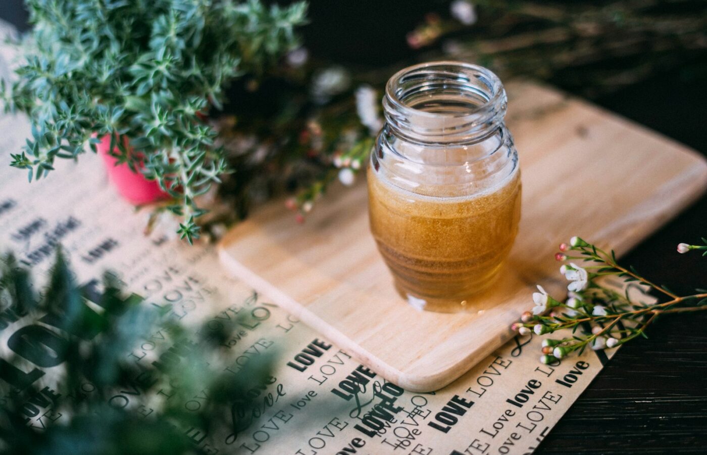 Glazen pot met honing, takjes verse tijm en teentjes knoflook op een houten tafel