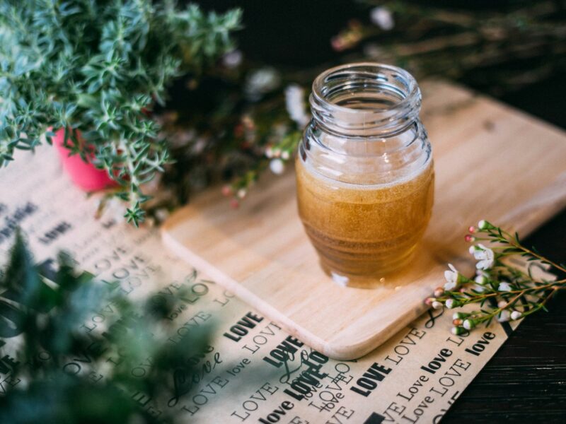 Glazen pot met honing, takjes verse tijm en teentjes knoflook op een houten tafel