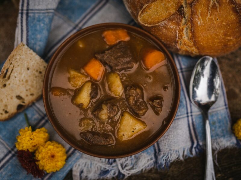 Een slowcooker met stoofvlees en uien in donkere saus