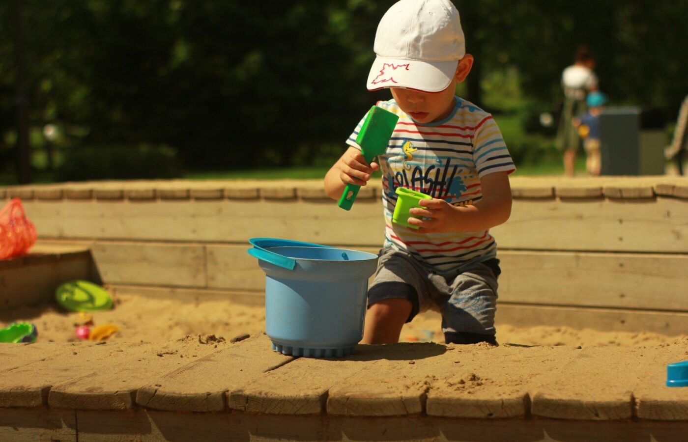 Peuter speelt in een houten zandbak in de tuin