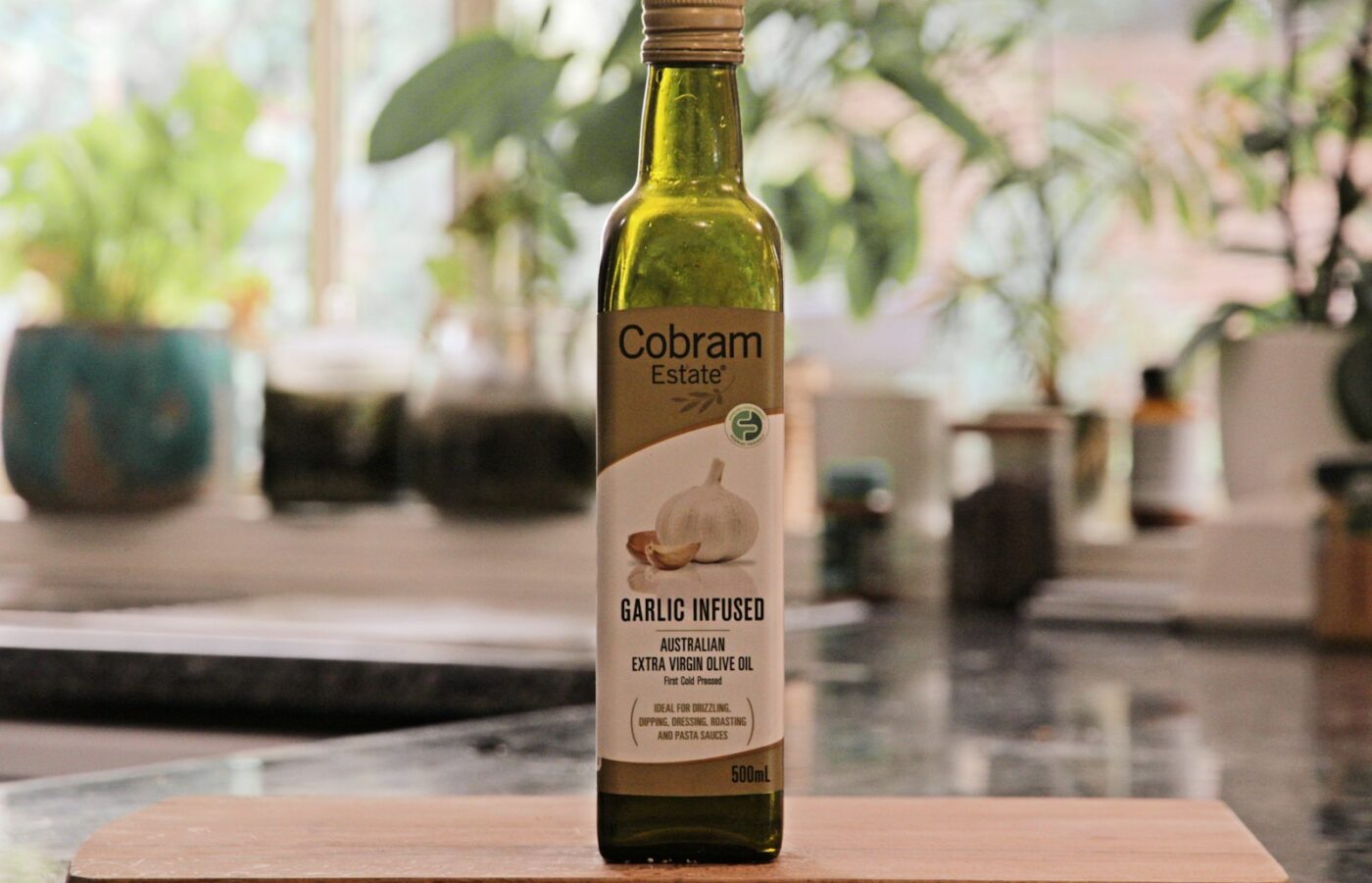 Fles olijfolie met etiket naast olijven op een houten keukenblad