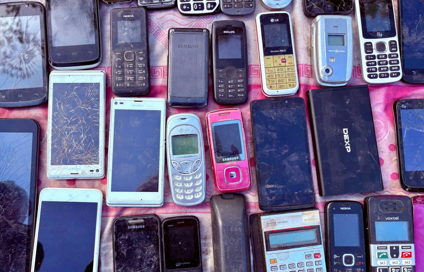 Een paar oude smartphones naast elkaar in een houten la