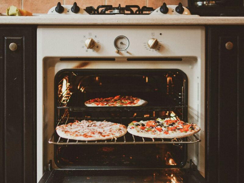 Iemand maakt de binnenkant van een oven schoon met een doek